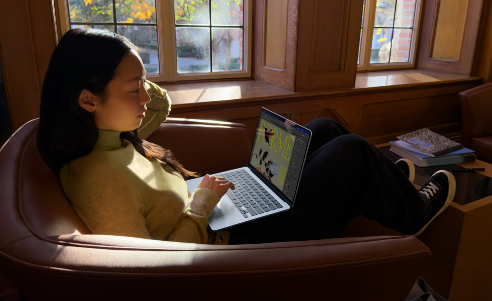 Une personne assise dans un fauteuil utilise un MacBook Air