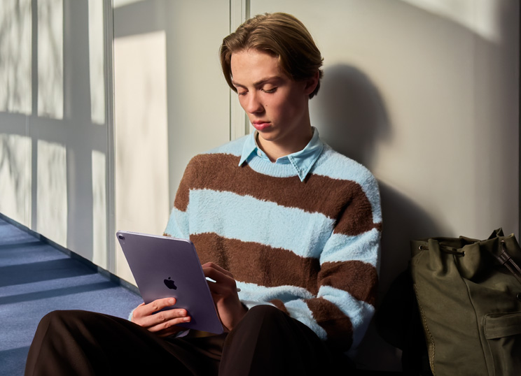 En person sidder på gulvet i et lyst rum og bruger iPad og Apple Pencil.